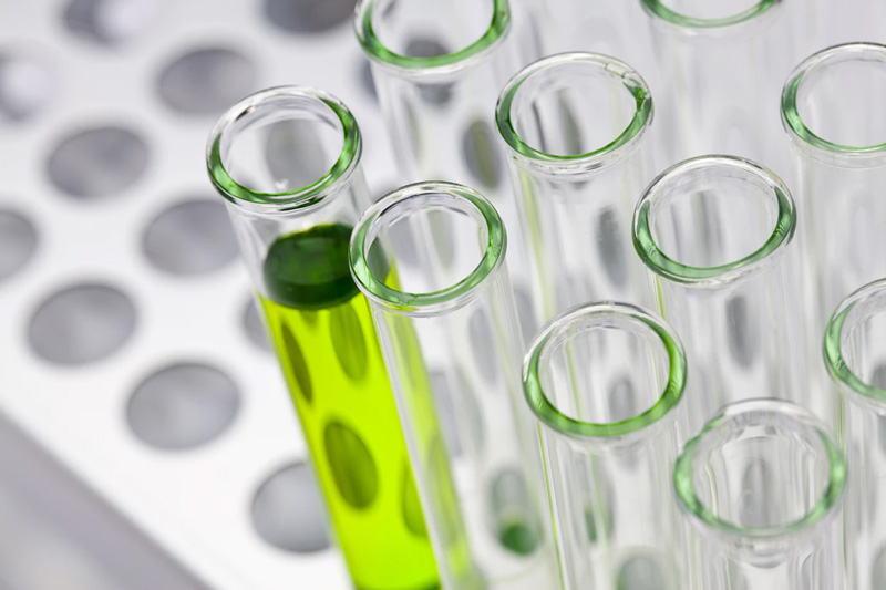 A tray of test tubes with one containing green liquid