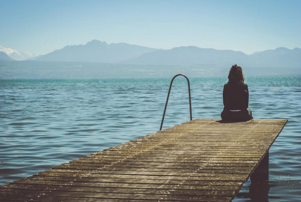 A woman sitting at the end of a dock in the daytime.