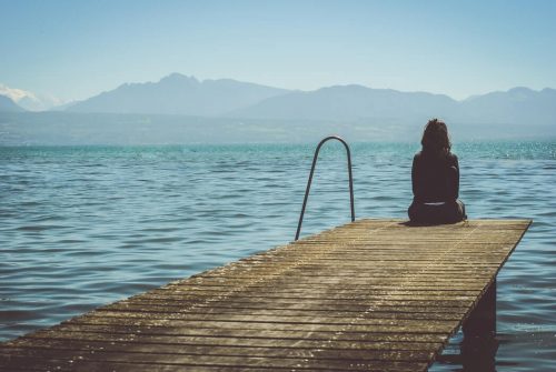A woman sitting at the end of a dock in the daytime.